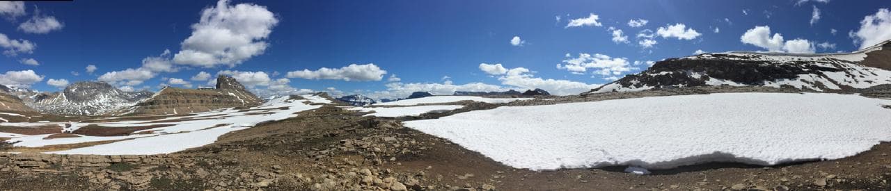 A high plateau snowfield under deep blue sky with flat-topped peaks beyond