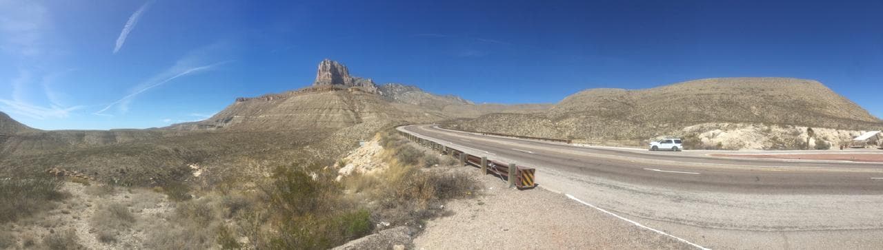 A highway curving past a stepped carbonate escarpment in arid country